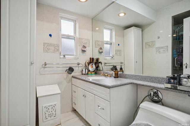 bathroom featuring a wealth of natural light, vanity, toilet, and tile walls