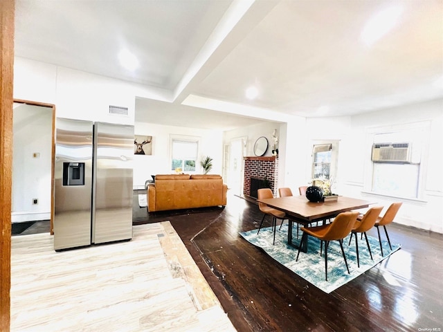 240 Pine St, Freeport, NY 11520 - dining space with beam ceiling, a fireplace, a wall unit AC, and light hardwood / wood-style flooring