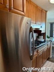 18-05 215th St Unit 16S, Bayside, NY 11360 - kitchen with freestanding refrigerator and brown cabinets