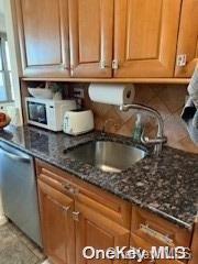 kitchen featuring stainless steel dishwasher, sink, and dark stone counters