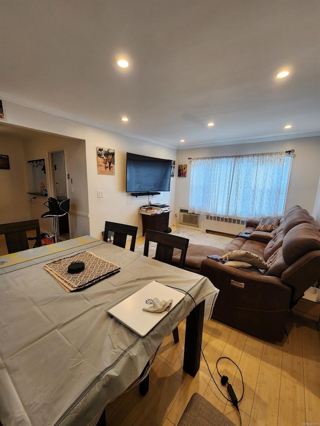 dining room with a wall mounted air conditioner, ornamental molding, and light wood-type flooring