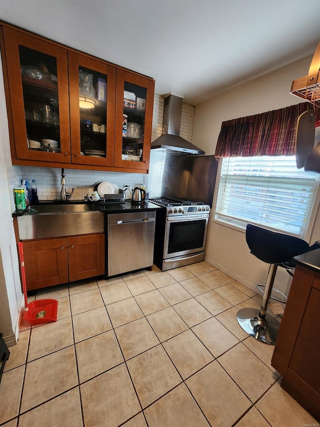 kitchen with light tile patterned floors, sink, appliances with stainless steel finishes, decorative backsplash, and wall chimney exhaust hood