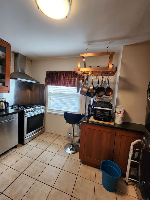 kitchen with light tile patterned flooring, wall chimney exhaust hood, and stainless steel appliances