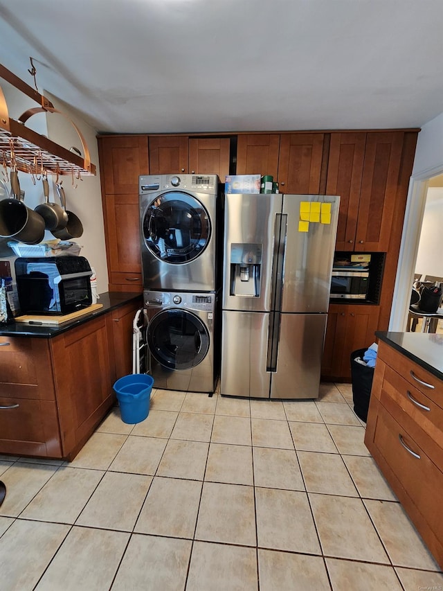 laundry area with light tile patterned flooring and stacked washing maching and dryer