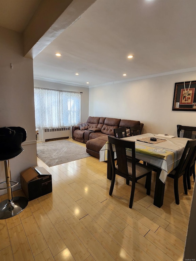 dining space featuring ornamental molding, radiator heating unit, and light wood-type flooring