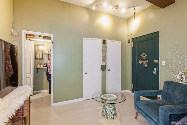 sitting room with track lighting, tile patterned floors, and a high ceiling