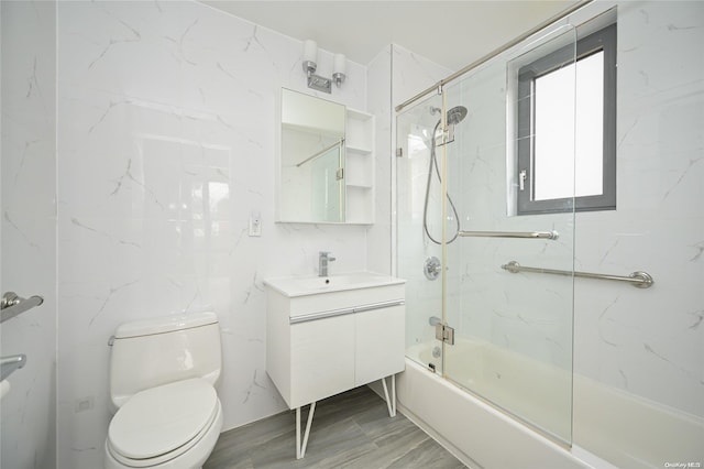 full bathroom featuring hardwood / wood-style floors, vanity, bath / shower combo with glass door, and toilet