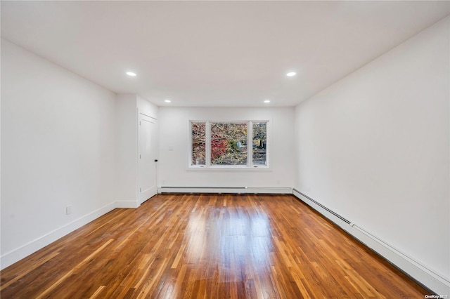 empty room with hardwood / wood-style floors and baseboard heating