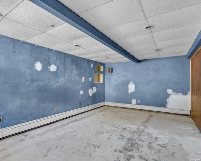 unfurnished room featuring concrete floors, baseboard heating, and a drop ceiling