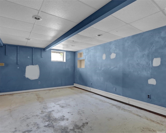 basement featuring a drop ceiling and a baseboard heating unit