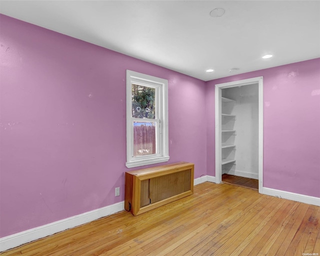 unfurnished bedroom featuring a spacious closet, light wood-type flooring, and a closet