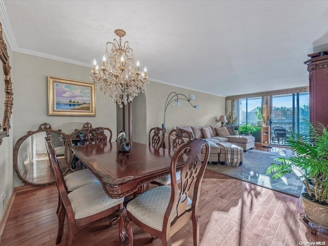 dining space with crown molding, wood-type flooring, a textured ceiling, and an inviting chandelier