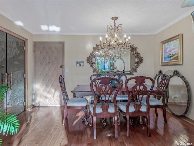 dining room with hardwood / wood-style floors, ornamental molding, and an inviting chandelier