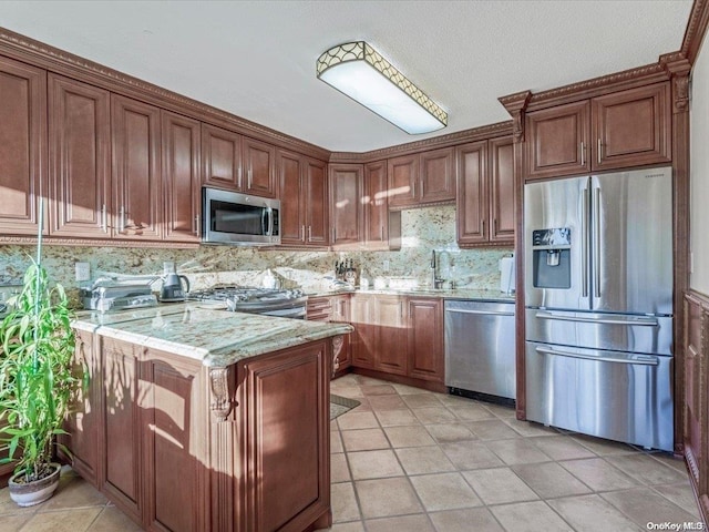 kitchen with backsplash, a textured ceiling, appliances with stainless steel finishes, light stone counters, and kitchen peninsula