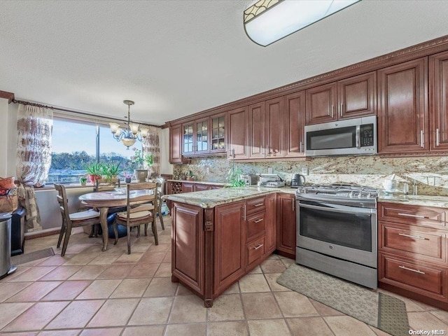 kitchen with pendant lighting, light stone countertops, tasteful backsplash, stainless steel appliances, and a chandelier