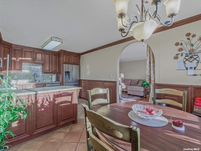 kitchen featuring pendant lighting, crown molding, sink, stainless steel fridge, and a notable chandelier