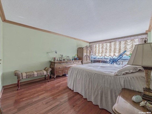 bedroom with hardwood / wood-style flooring, ornamental molding, and a textured ceiling