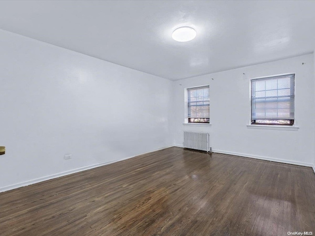 unfurnished room with dark hardwood / wood-style flooring and radiator