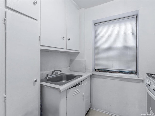 kitchen featuring white range, white cabinetry, and sink