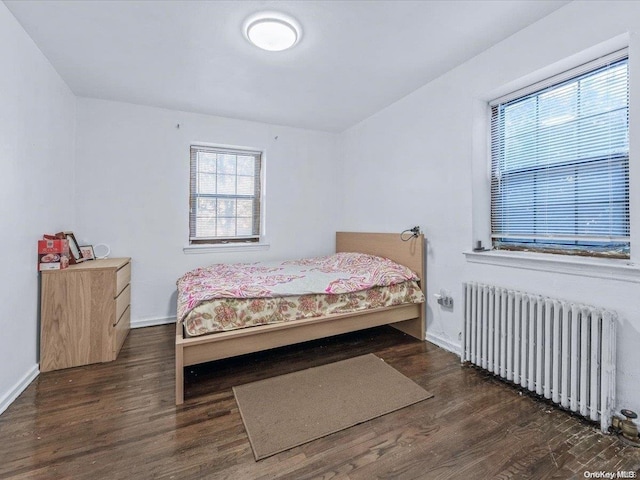 bedroom featuring radiator heating unit and dark hardwood / wood-style floors