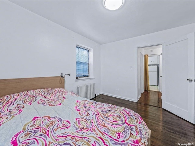 bedroom with dark hardwood / wood-style floors, white refrigerator, and radiator