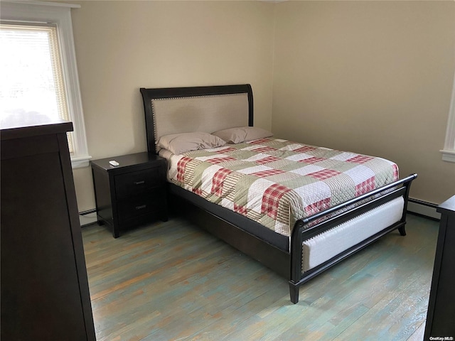 bedroom featuring hardwood / wood-style flooring and a baseboard heating unit