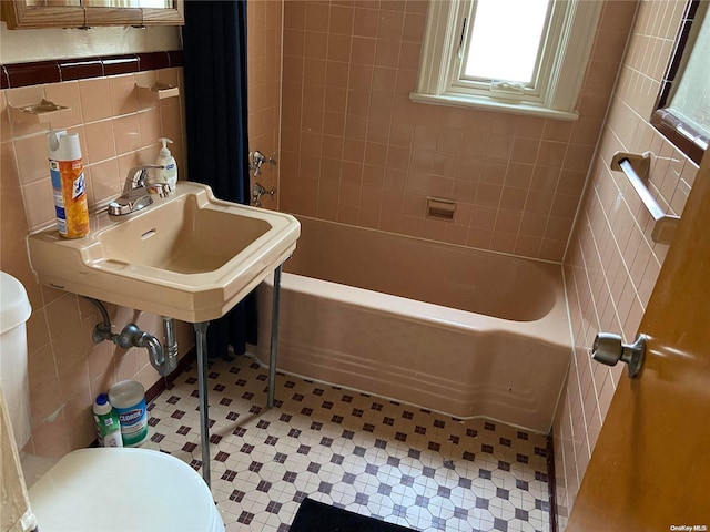 full bathroom featuring sink, bathtub / shower combination, tile walls, and toilet