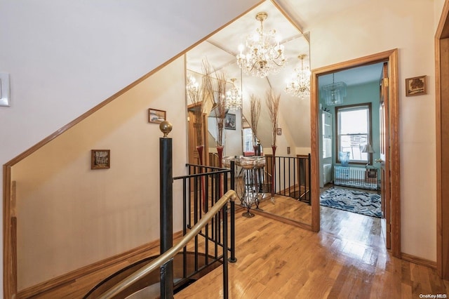 hall with radiator, hardwood / wood-style floors, and a chandelier