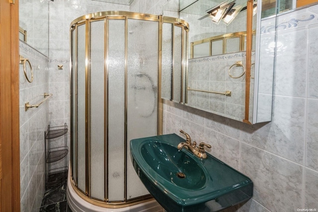 bathroom featuring tile walls, a shower with shower door, and sink