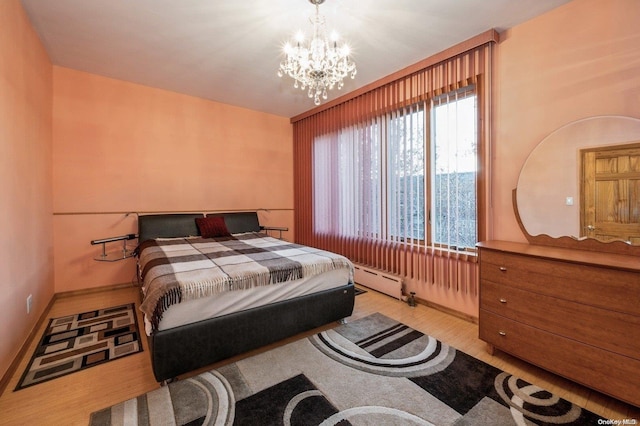 bedroom featuring an inviting chandelier, light hardwood / wood-style floors, and a baseboard heating unit