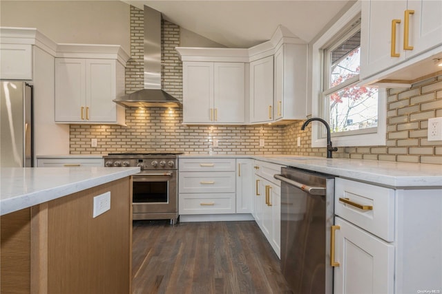 kitchen with white cabinetry, wall chimney exhaust hood, dark wood-type flooring, stainless steel appliances, and light stone counters