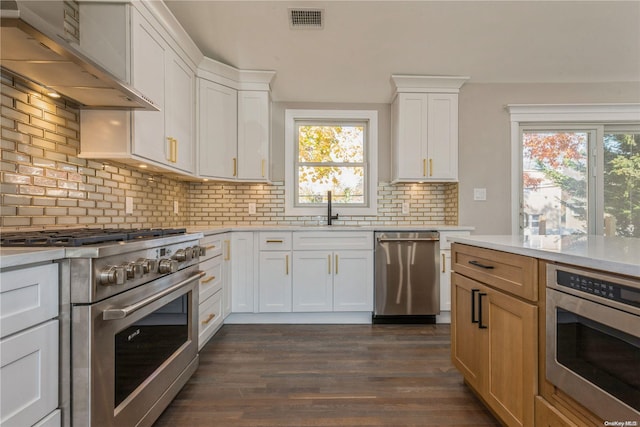 kitchen featuring white cabinetry, dark hardwood / wood-style flooring, wall chimney range hood, and appliances with stainless steel finishes