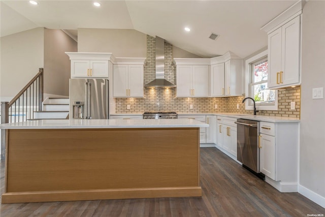 kitchen featuring appliances with stainless steel finishes, dark hardwood / wood-style floors, a kitchen island, and wall chimney exhaust hood