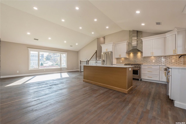 kitchen featuring dark hardwood / wood-style flooring, high end appliances, wall chimney range hood, white cabinets, and a kitchen island