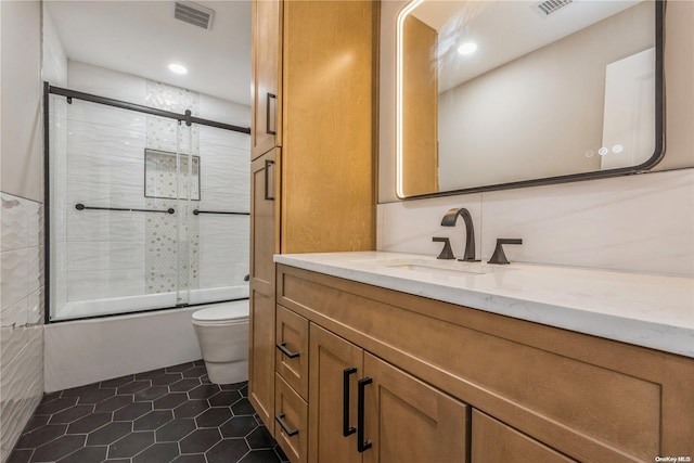 full bathroom with combined bath / shower with glass door, vanity, tile patterned floors, and toilet