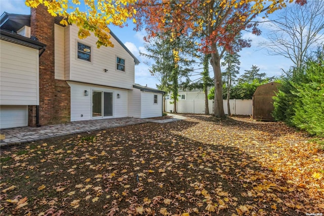 back of property with a patio and a storage shed