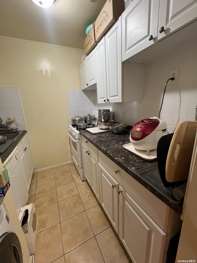 kitchen with dark stone counters, white cabinets, decorative backsplash, light tile patterned floors, and white range with gas stovetop