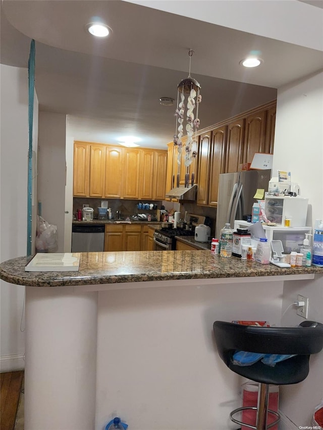 kitchen with a kitchen breakfast bar, kitchen peninsula, exhaust hood, and appliances with stainless steel finishes