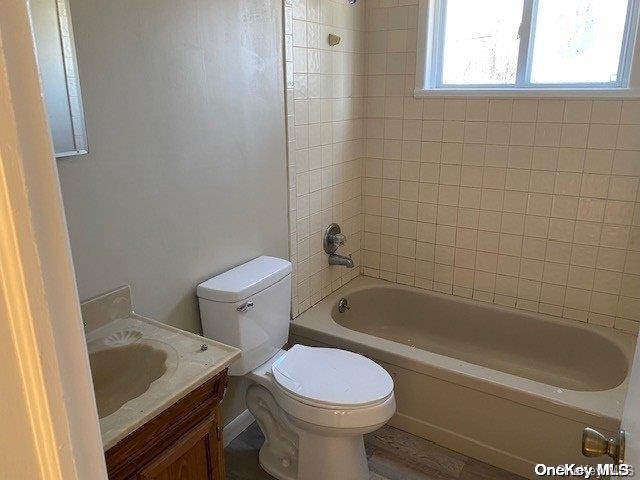 full bathroom featuring tiled shower / bath, vanity, and toilet