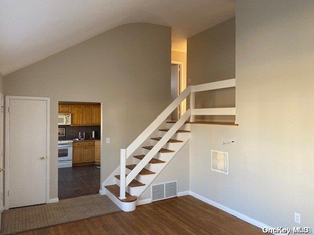 staircase with lofted ceiling and hardwood / wood-style flooring