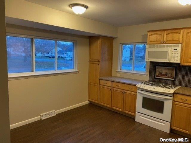 kitchen with decorative backsplash, dark wood-type flooring, and white appliances