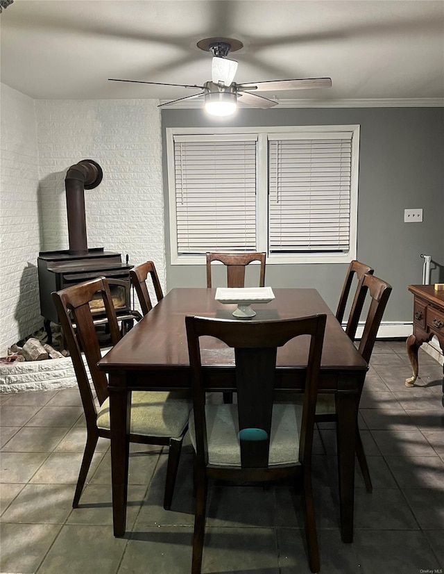 dining area featuring tile patterned flooring, crown molding, ceiling fan, and a wood stove