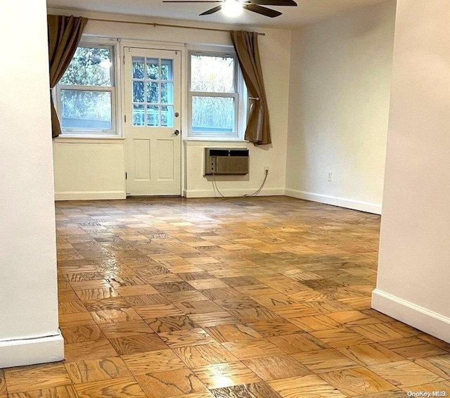 empty room with an AC wall unit, ceiling fan, plenty of natural light, and light parquet flooring