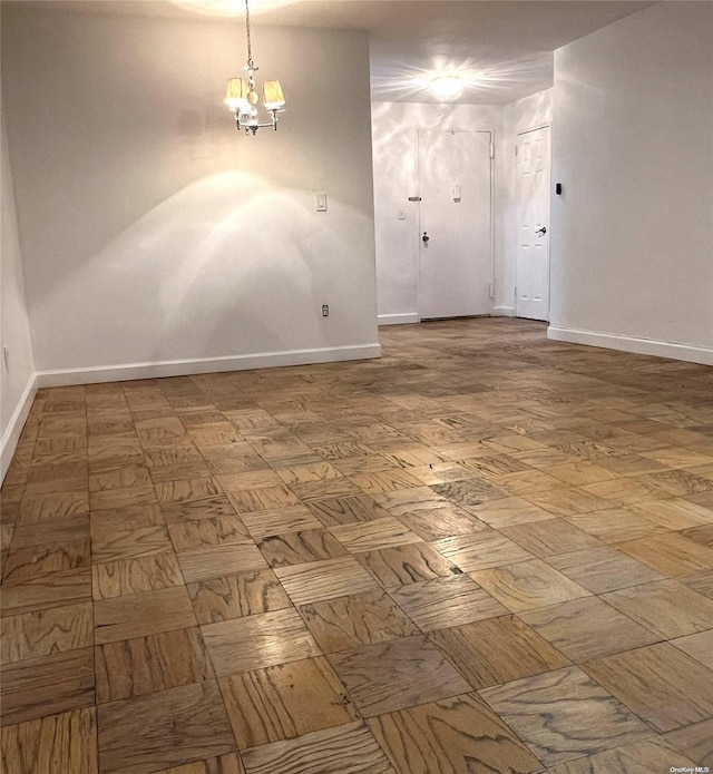 empty room featuring parquet floors and a notable chandelier