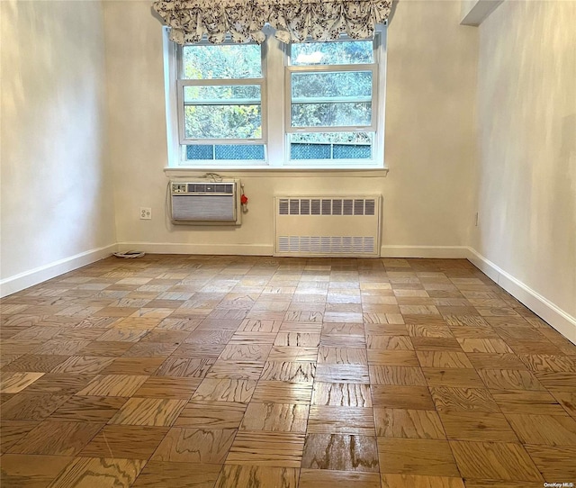 spare room featuring radiator, light parquet floors, and a wall mounted air conditioner