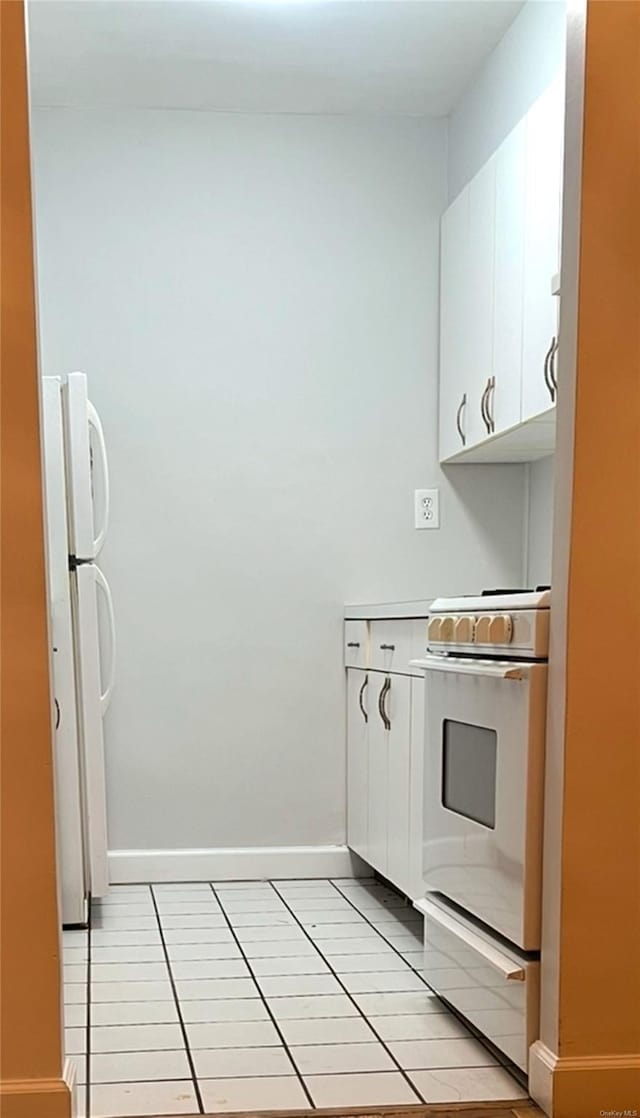 kitchen with white cabinets, stove, white fridge, and light tile patterned flooring