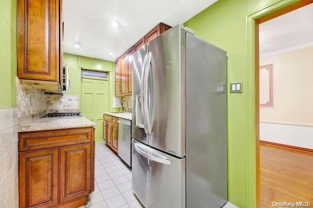 kitchen featuring sink, backsplash, crown molding, light tile patterned floors, and appliances with stainless steel finishes