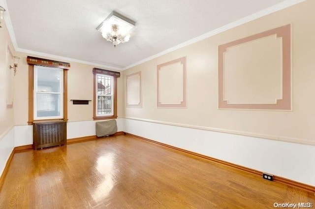 spare room featuring hardwood / wood-style floors, radiator, and crown molding