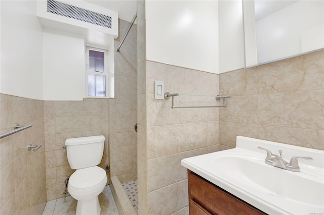 bathroom featuring tiled shower, vanity, toilet, and tile walls