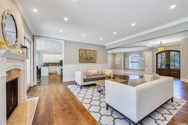 living room featuring french doors, a premium fireplace, ornamental molding, and light hardwood / wood-style flooring